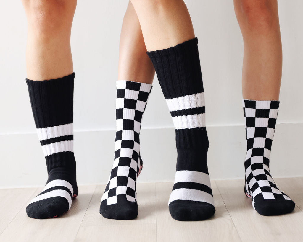 Black and white striped socks worn by people on a light wooden floor.
