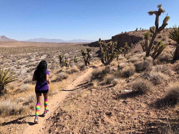 trail runner running through desert in rainbow compression socks