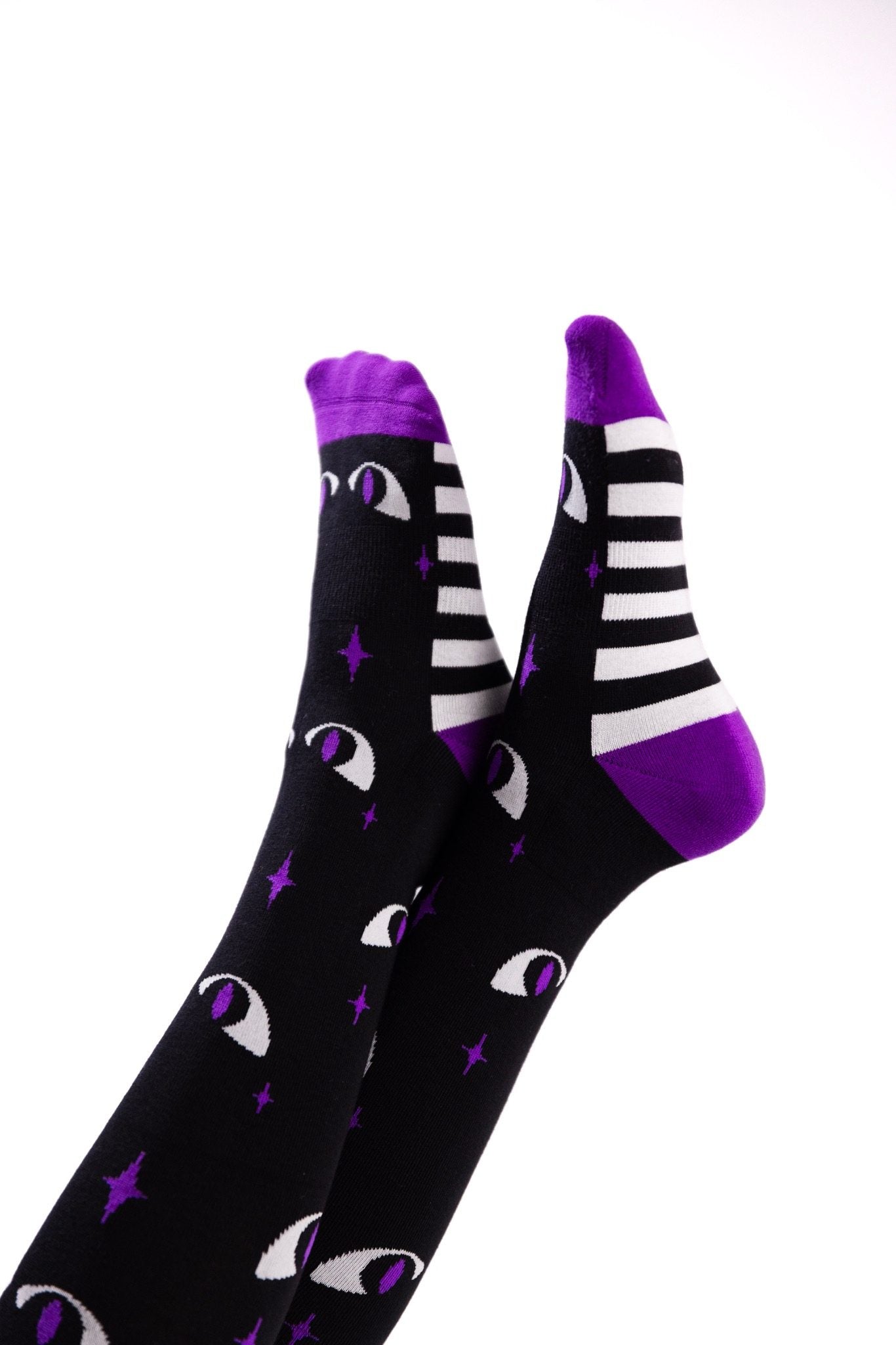 Black knee-high socks with purple cuffs, toes and heels, featuring white cat eyes with purple pupils, purple stars, and black-and-white stripes along the feet.