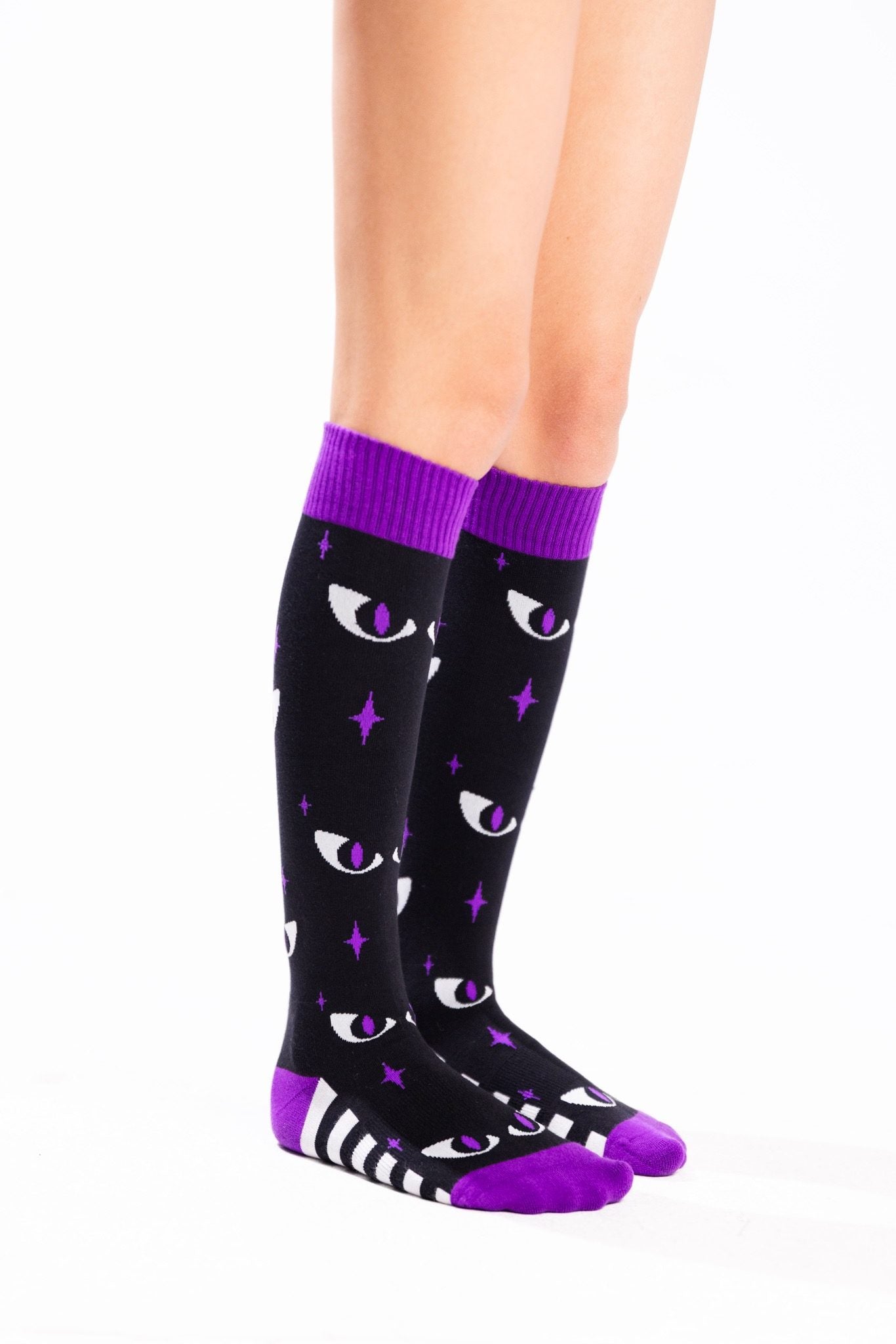Black knee-high socks with purple cuffs, toes and heels, featuring white cat eyes with purple pupils, purple stars, and black-and-white stripes along the feet.