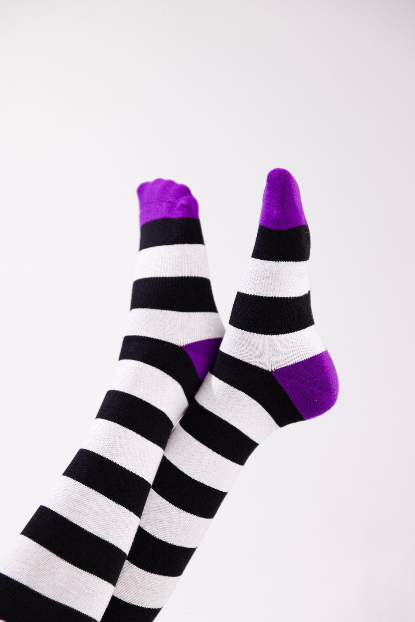 Black-and-white striped thigh-high socks with bright purple toes and heels.