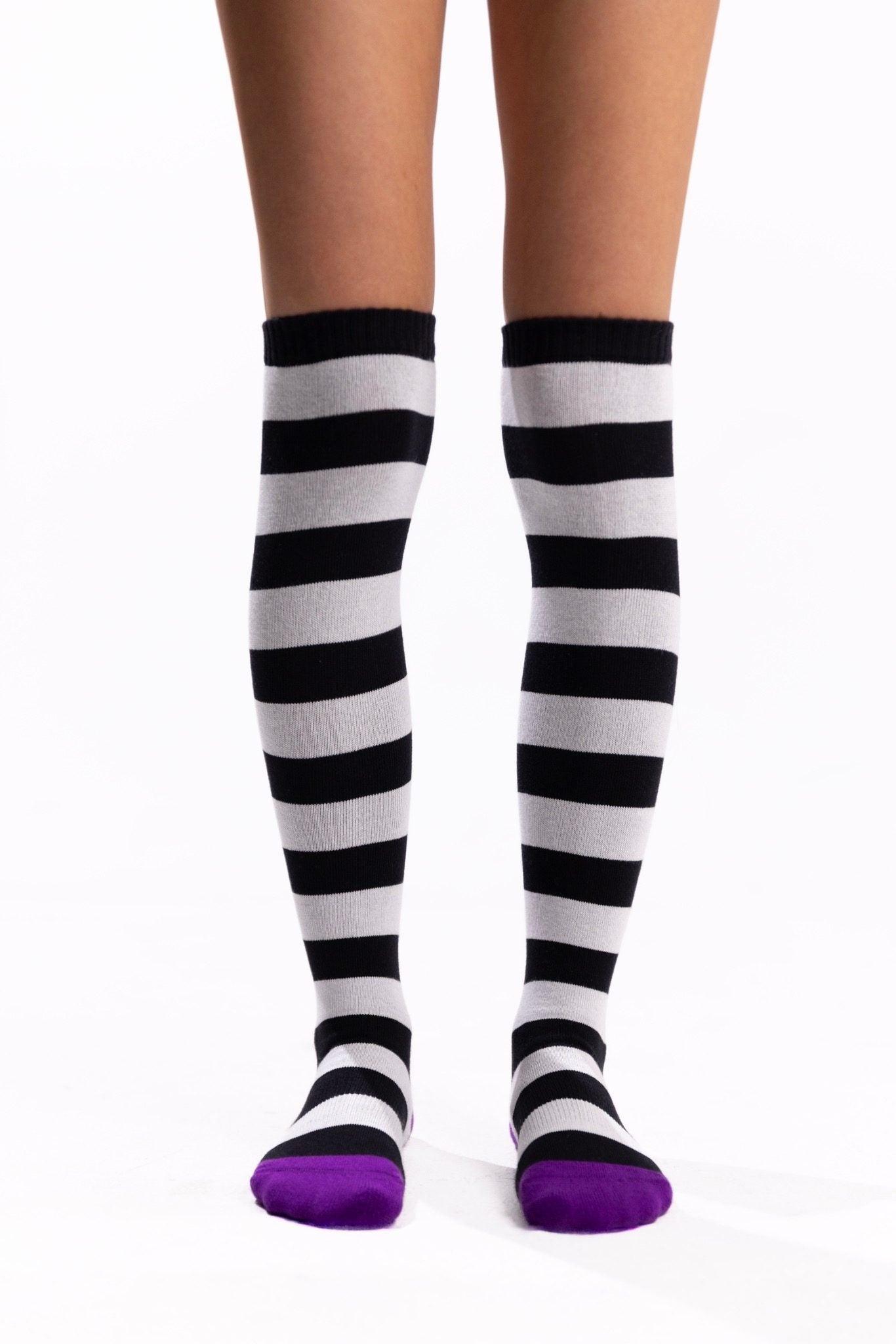Black-and-white striped thigh-high socks with bright purple toes and heels.