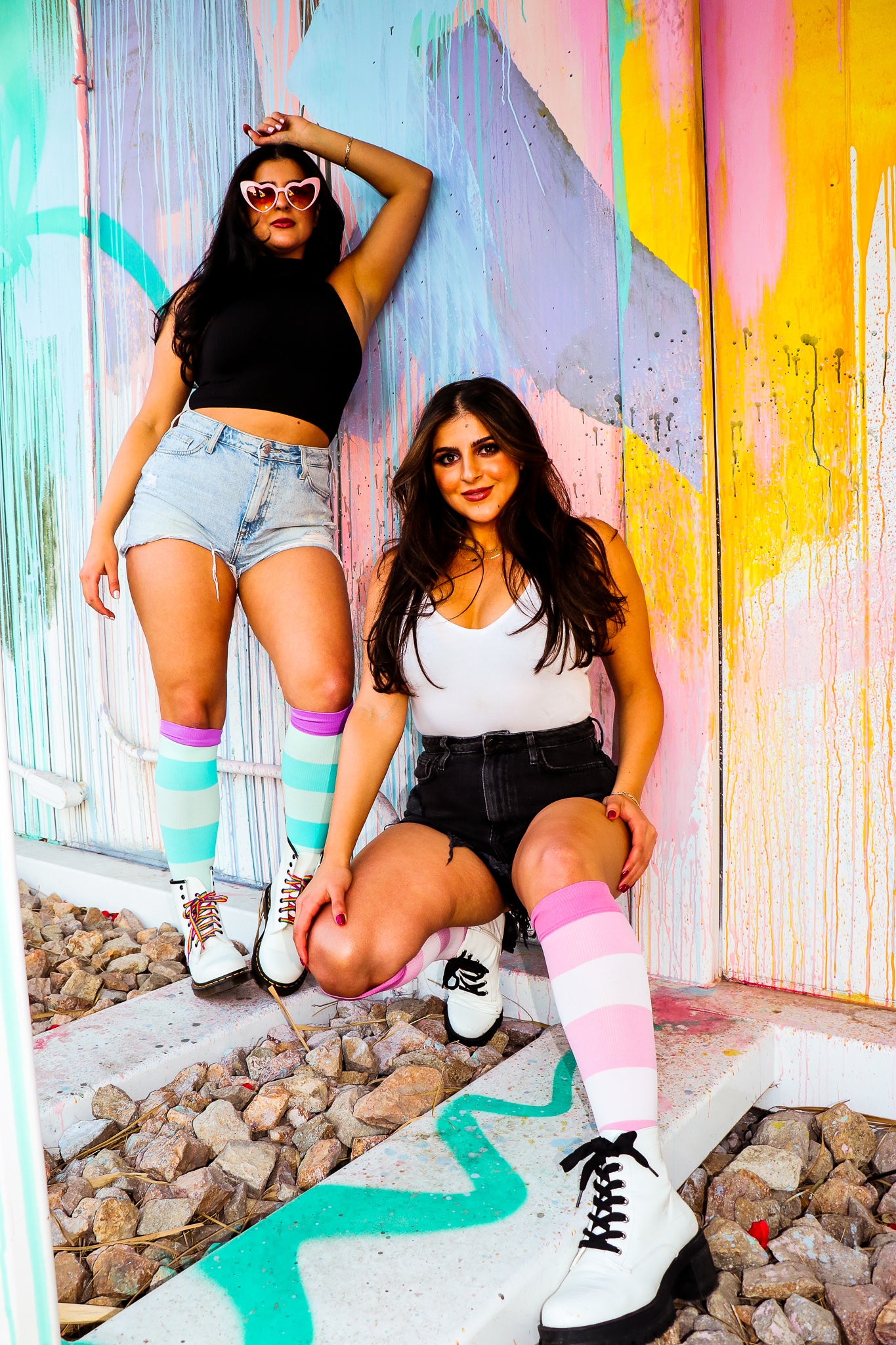 compression socks in pink aqua and lavender purple on two beautiful women standing in front of a colorful wall