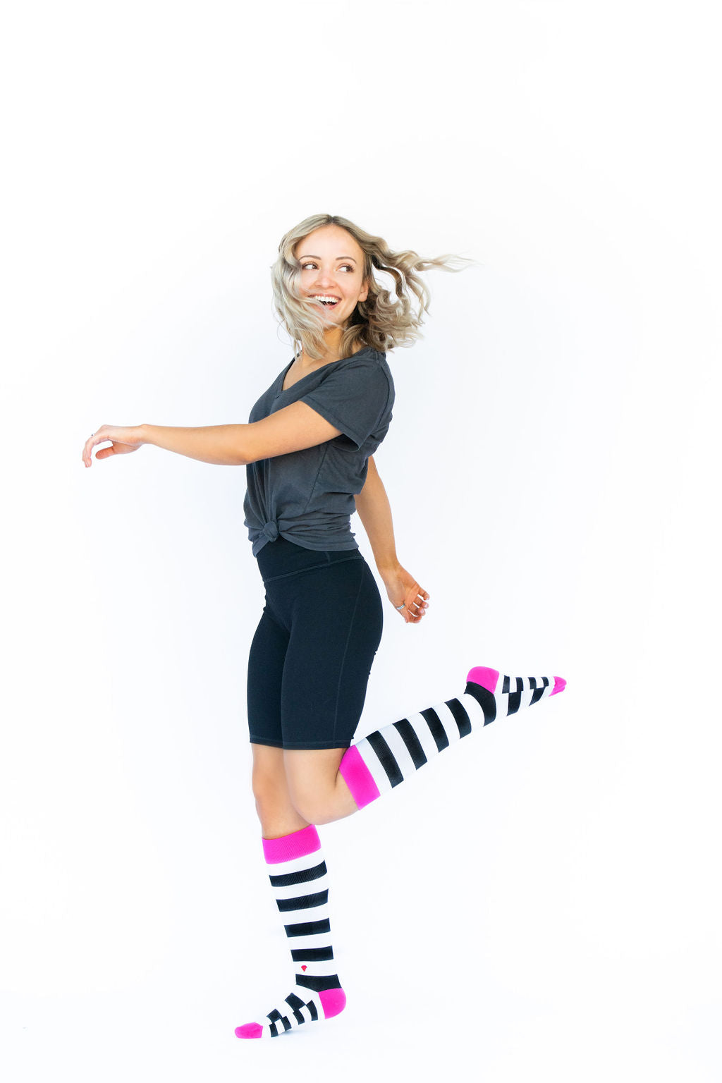 compression socks in black and white stripes with hot pink accents on the legs of a beautiful blonde woman 