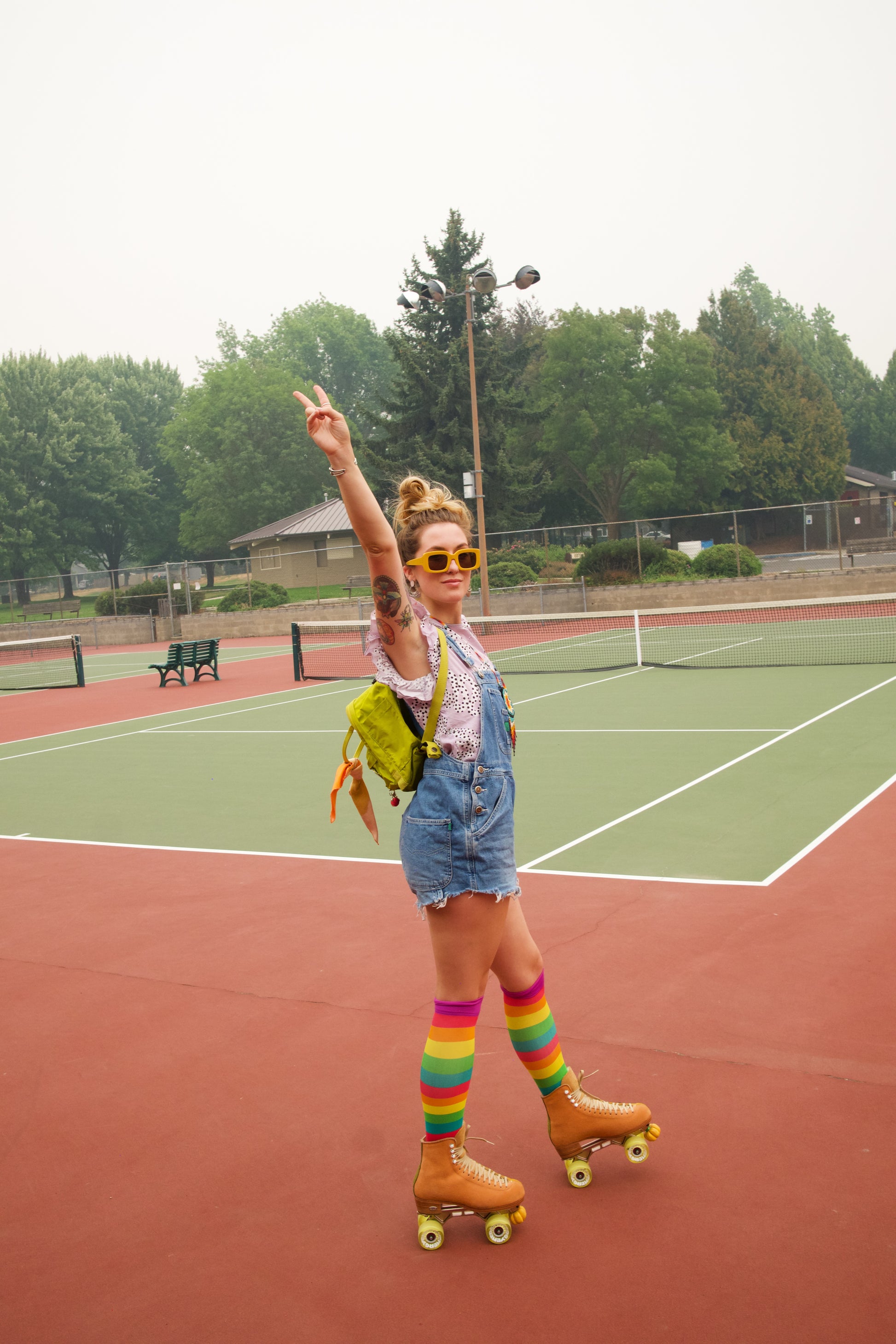 compression socks with rainbow stripes in pink, orange, yellow, green, and teal with purple accents worn by a roller skater on a tennis court
