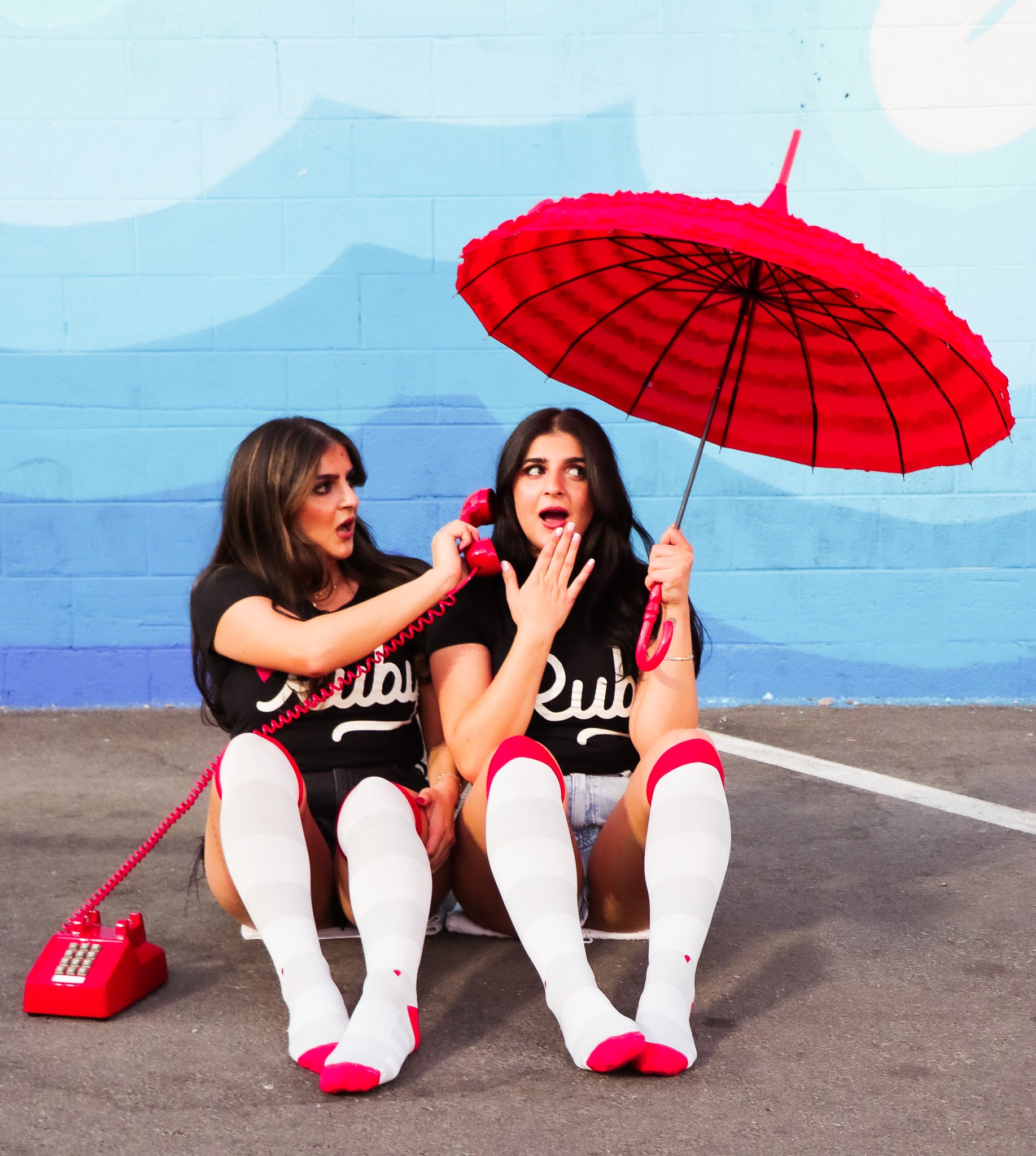 compression socks with grey stripes and red accents worn by twins using a red vintage telephone and pointy red parasol