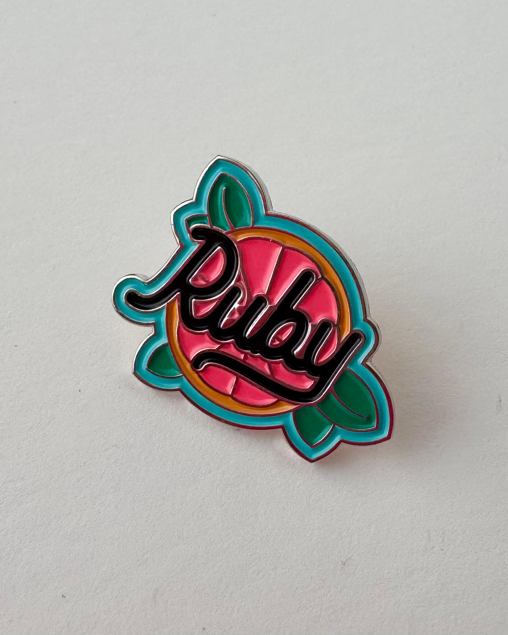 Colorful enamel pin with 'Ruby' text on a grapefruit background
